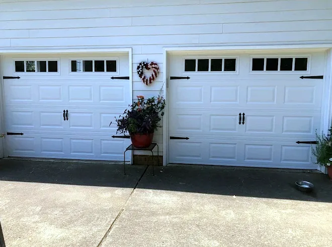 Two white carriage-style doors with black hinges and handles